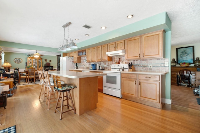 kitchen with a center island, white appliances, ceiling fan, tasteful backsplash, and decorative light fixtures