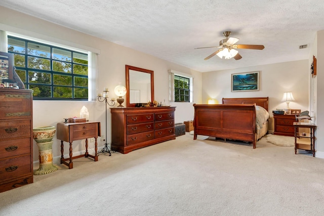 carpeted bedroom with multiple windows, ceiling fan, and a textured ceiling