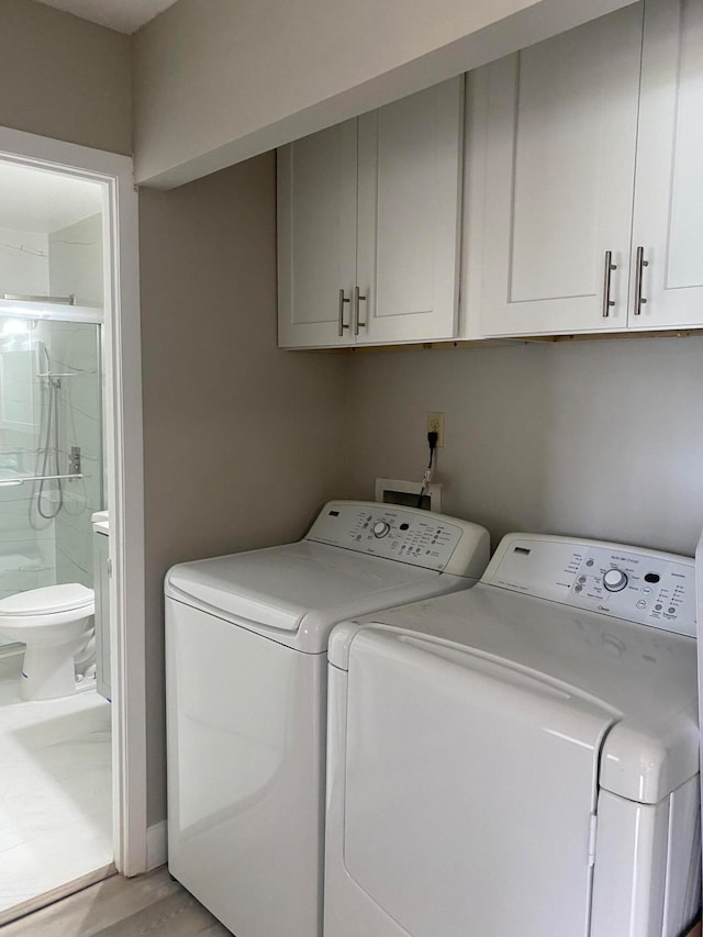 laundry area with washing machine and dryer, light hardwood / wood-style flooring, and cabinets