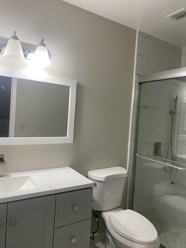 bathroom with a shower with shower door, vanity, and toilet