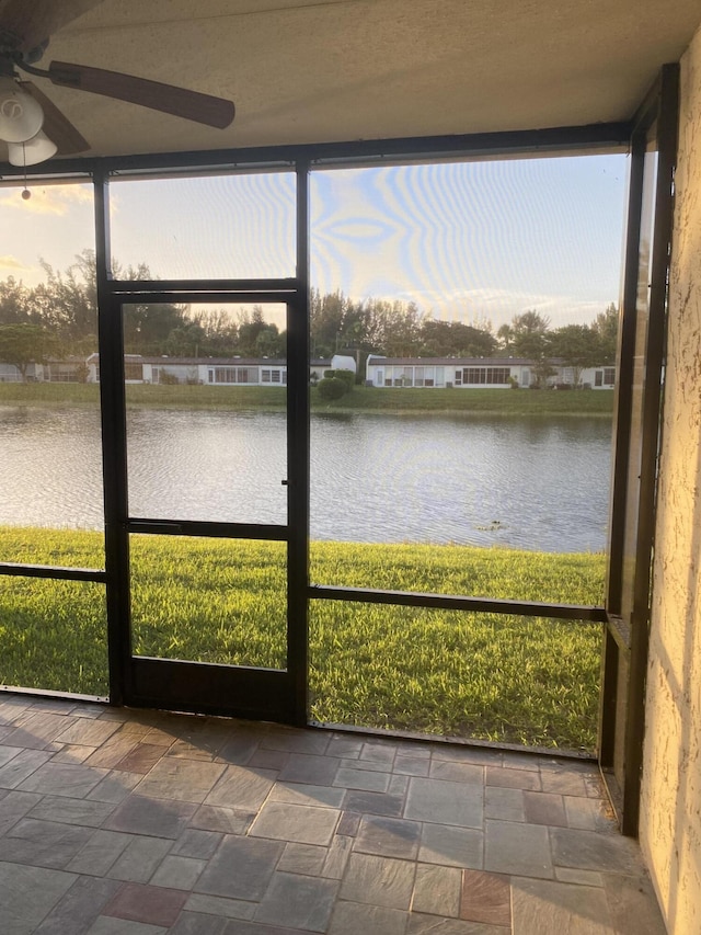 unfurnished sunroom with ceiling fan and a water view