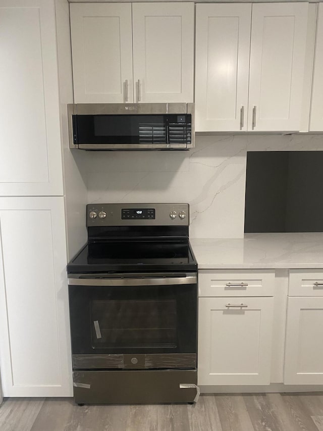 kitchen featuring stainless steel appliances, light hardwood / wood-style flooring, white cabinets, and decorative backsplash