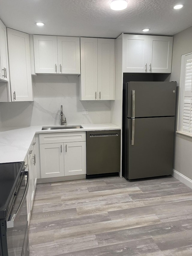 kitchen featuring white cabinetry, dishwasher, sink, and stainless steel refrigerator