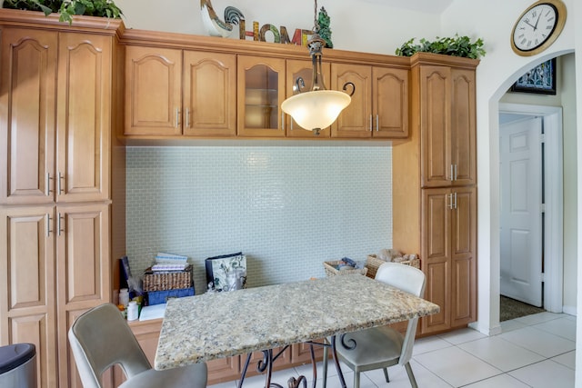 kitchen featuring a kitchen breakfast bar, tasteful backsplash, and light tile patterned floors