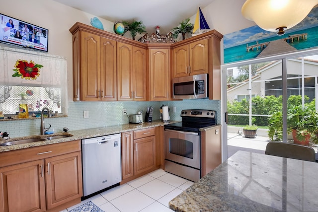 kitchen featuring decorative backsplash, sink, light stone counters, and stainless steel appliances