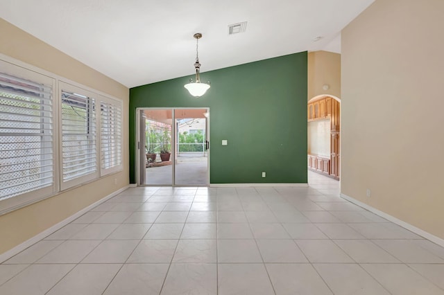 empty room featuring light tile patterned floors, visible vents, high vaulted ceiling, and baseboards