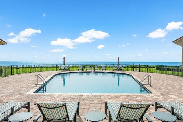 view of swimming pool with a patio area and a water view