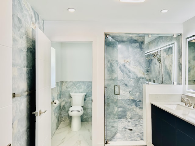 bathroom featuring walk in shower, vanity, toilet, and tile walls