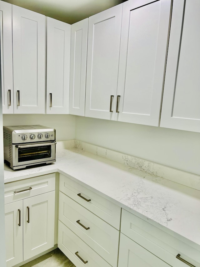 kitchen featuring light stone countertops and white cabinetry