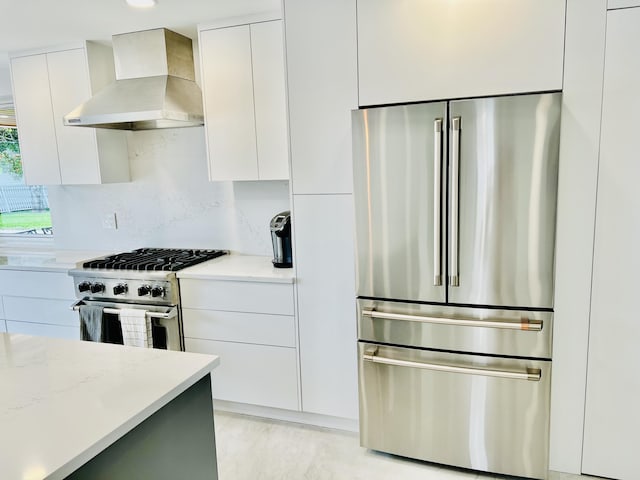 kitchen featuring light stone countertops, backsplash, wall chimney exhaust hood, premium appliances, and white cabinetry