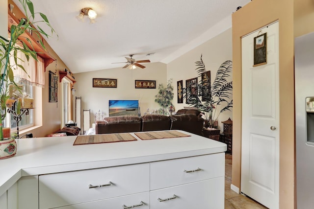 kitchen featuring lofted ceiling, light tile patterned flooring, kitchen peninsula, and ceiling fan