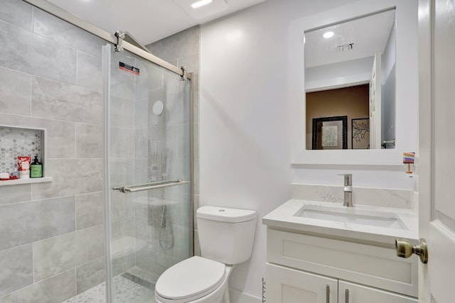 bathroom featuring toilet, vanity, and a shower with shower door