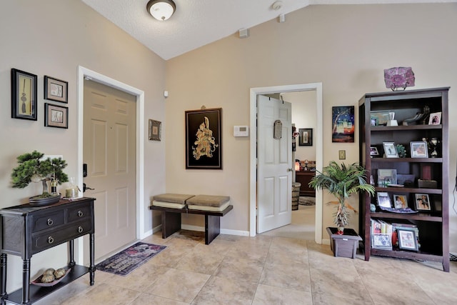 tiled foyer entrance with lofted ceiling and a textured ceiling