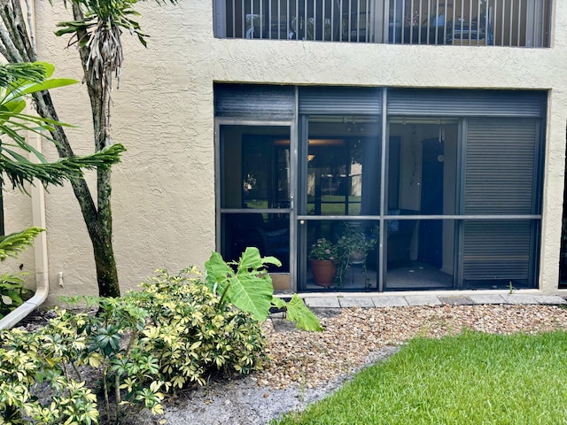 view of exterior entry featuring a balcony and stucco siding