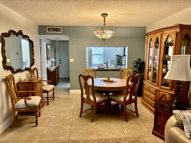 dining space featuring sink, tile patterned floors, and a textured ceiling