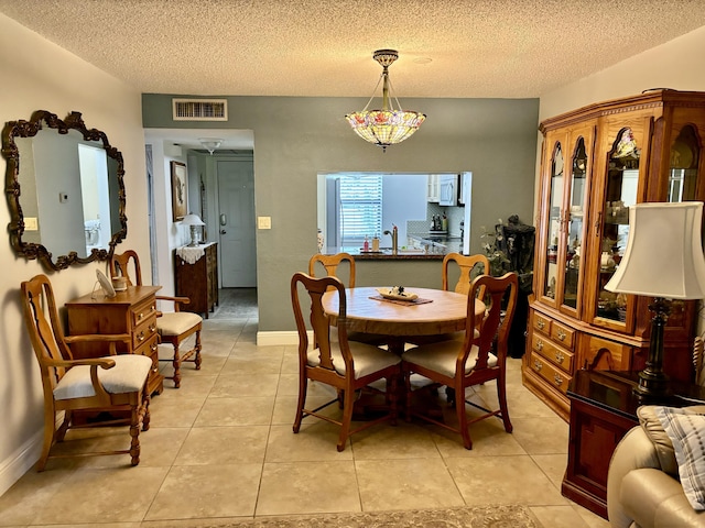 dining room with visible vents, a textured ceiling, baseboards, and light tile patterned floors