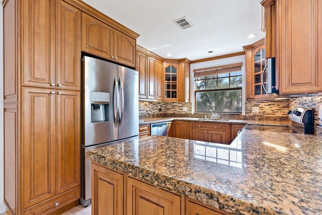 kitchen with a textured ceiling, light tile patterned flooring, sink, ornate columns, and stainless steel appliances