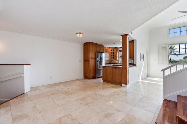 kitchen with decorative backsplash, ornate columns, crown molding, stainless steel fridge with ice dispenser, and light tile patterned floors