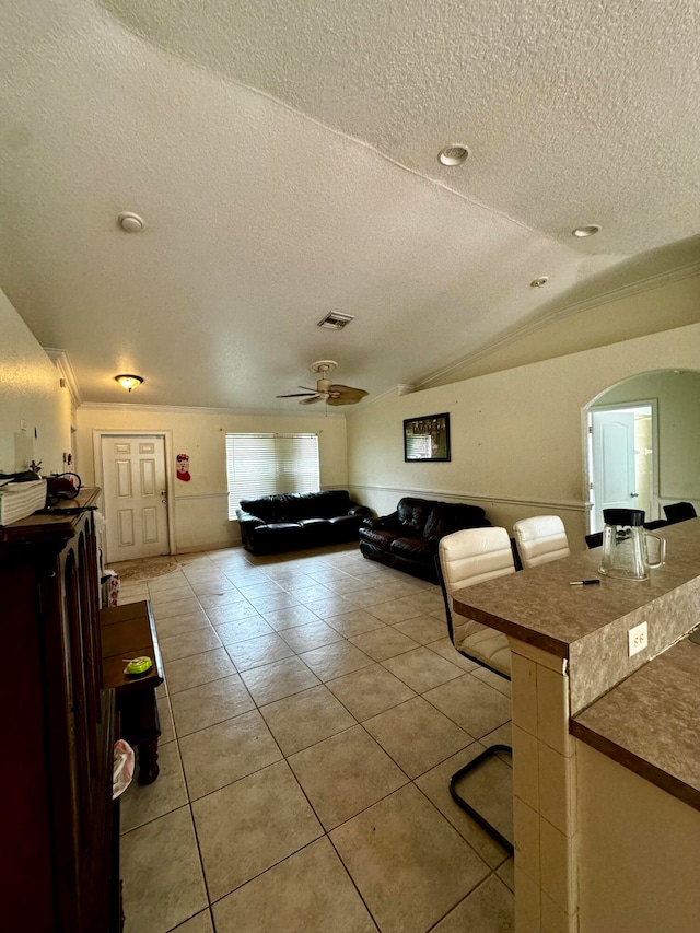 living room featuring ceiling fan, a textured ceiling, lofted ceiling, and tile patterned flooring