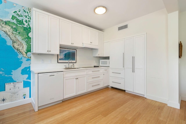 kitchen featuring white appliances, white cabinetry, light countertops, and a sink