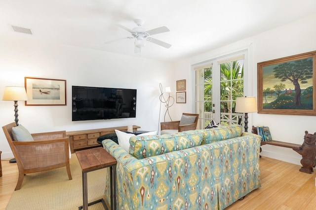 living area featuring baseboards, light wood finished floors, visible vents, and a ceiling fan