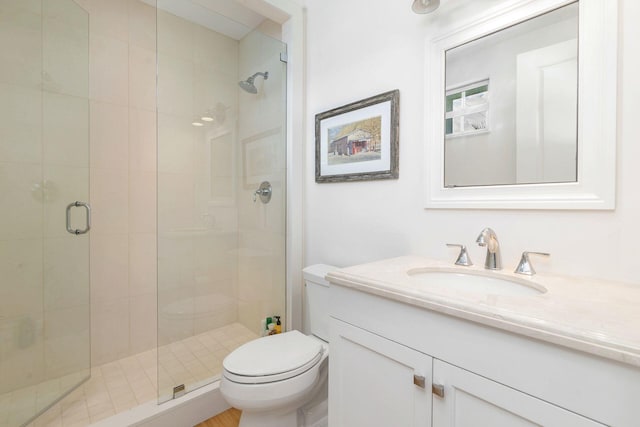 bathroom with a stall shower, vanity, and toilet