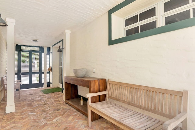 interior space with a textured ceiling, french doors, and brick floor