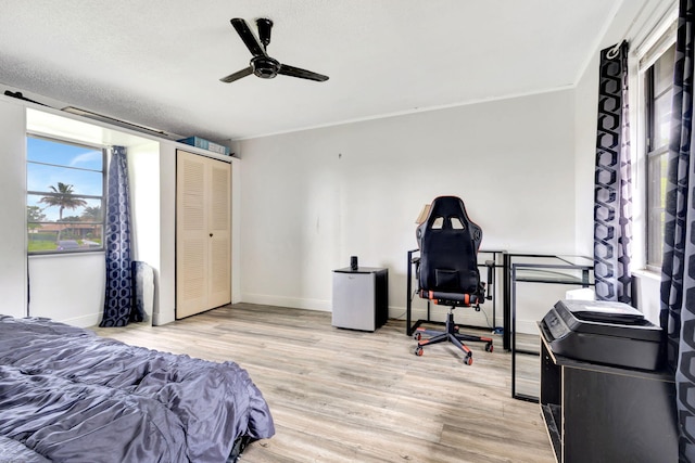 bedroom with ceiling fan, a textured ceiling, a closet, and light wood-type flooring