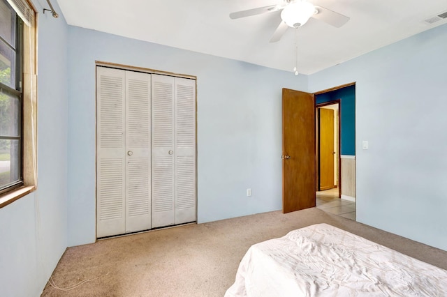 bedroom featuring ceiling fan, light colored carpet, and a closet