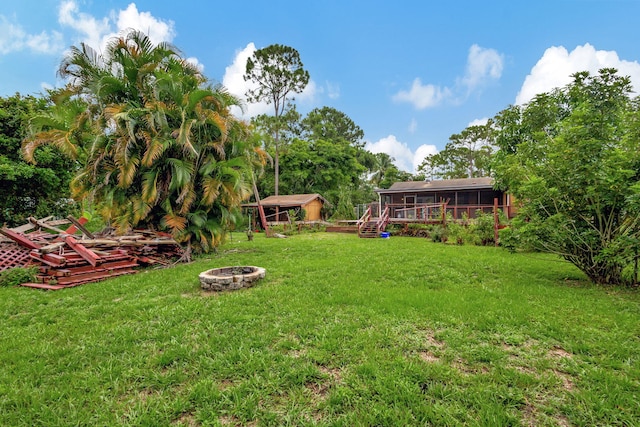 view of yard featuring an outdoor fire pit and a sunroom