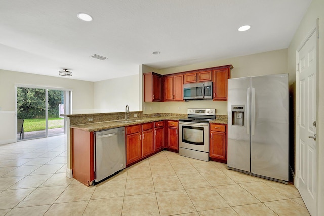 kitchen featuring kitchen peninsula, light tile patterned floors, stainless steel appliances, dark stone counters, and sink