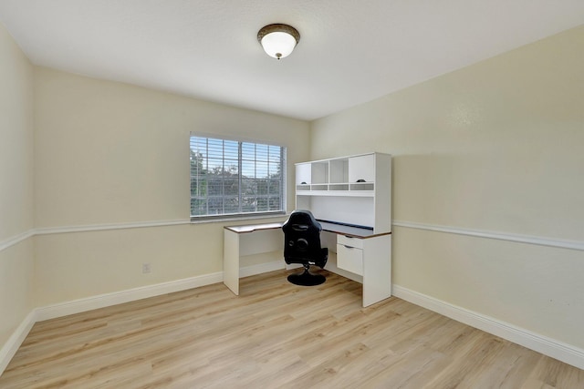 unfurnished office featuring light wood-type flooring and built in desk