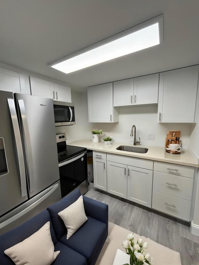 kitchen featuring sink, light hardwood / wood-style flooring, white cabinets, and stainless steel appliances