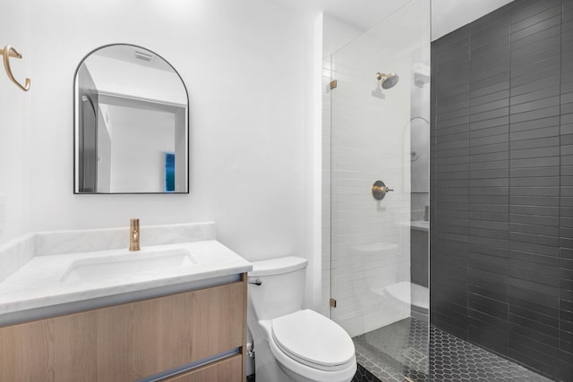 bathroom featuring vanity, a shower with door, and toilet