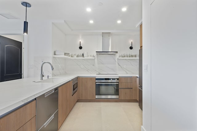 kitchen with sink, hanging light fixtures, stainless steel appliances, light stone countertops, and wall chimney exhaust hood