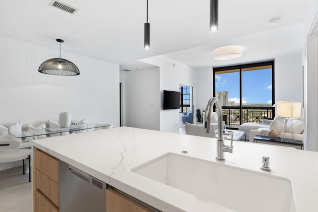 kitchen featuring sink, dishwasher, pendant lighting, a wall of windows, and light stone countertops