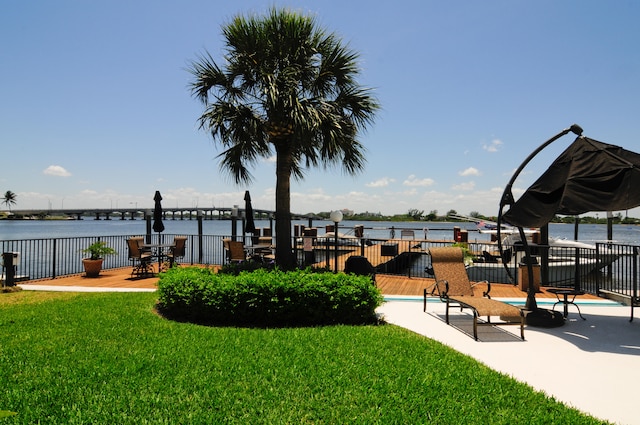 view of property's community with a patio area, a yard, and a water view