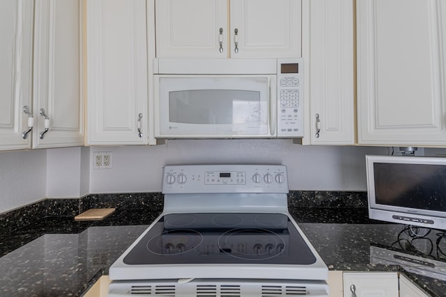 kitchen featuring white cabinetry, dark stone counters, and white appliances