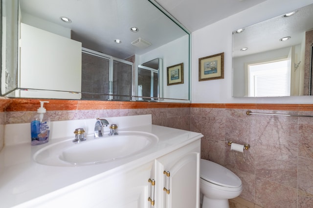 bathroom featuring tile walls, vanity, a shower with door, and toilet