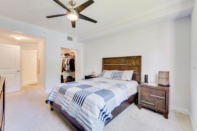 carpeted bedroom with ornamental molding, a closet, ceiling fan, and a walk in closet