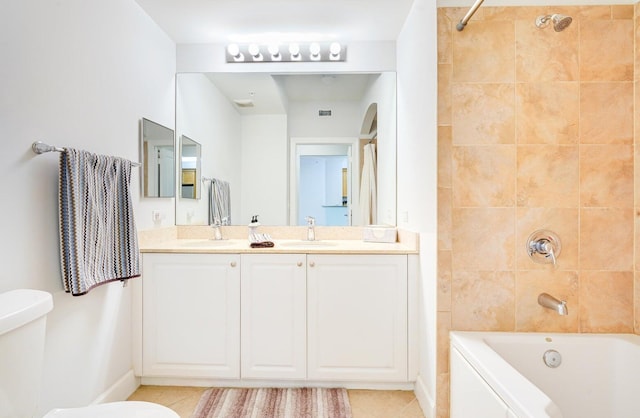 full bathroom with tiled shower / bath combo, toilet, double sink vanity, and tile patterned flooring