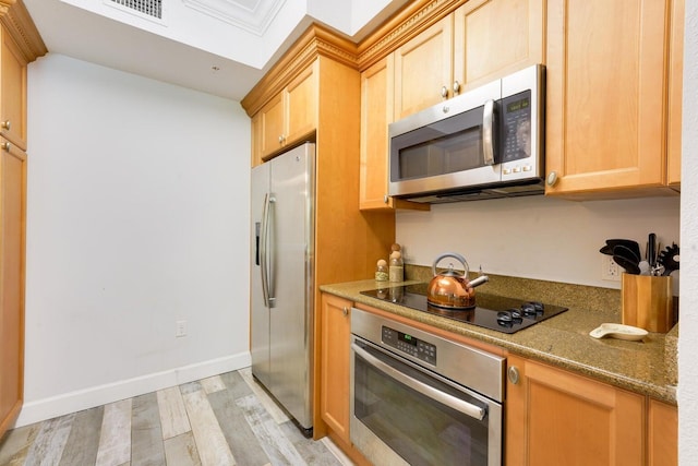 kitchen featuring dark stone counters, light brown cabinets, light wood-type flooring, and stainless steel appliances