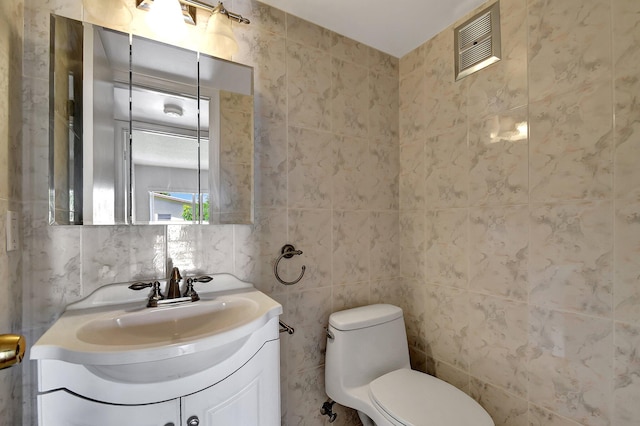 bathroom featuring tile walls, vanity, and toilet