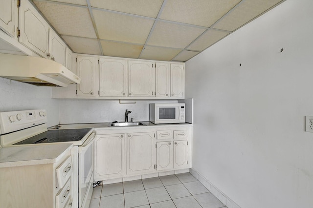 kitchen featuring a paneled ceiling, white appliances, sink, and light tile patterned floors