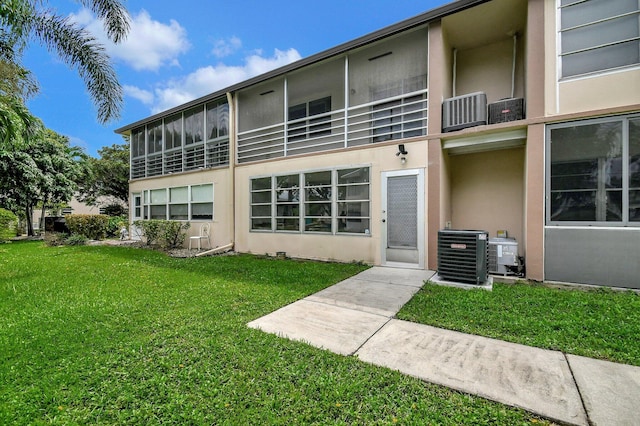 rear view of property featuring a balcony, a yard, and central air condition unit