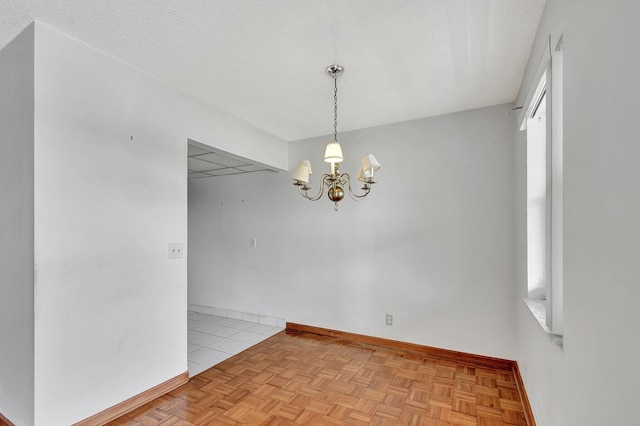 spare room featuring a notable chandelier, a textured ceiling, and light parquet floors