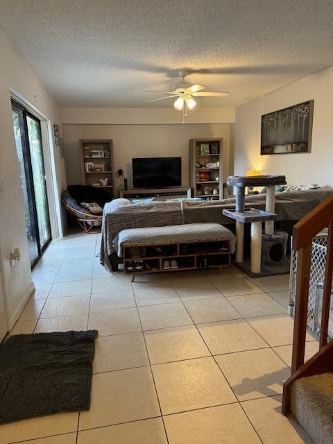 bedroom featuring ceiling fan, light tile patterned floors, and a textured ceiling