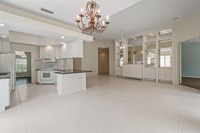 kitchen featuring white cabinets, a notable chandelier, light tile patterned flooring, and white appliances