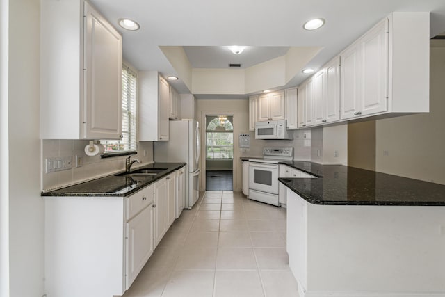 kitchen with white cabinets, a raised ceiling, white appliances, and dark stone countertops