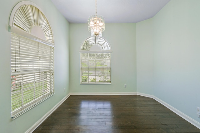 unfurnished dining area featuring dark wood-type flooring and an inviting chandelier